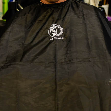 Black cutting cape from King & Country Grooming RESERVE men's hair styling products.